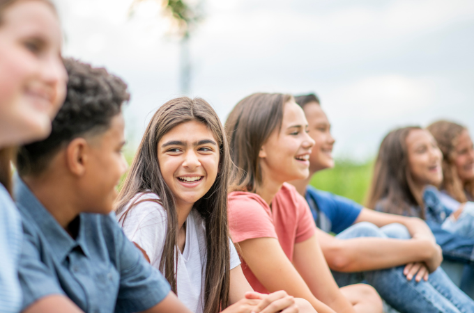 a group of young teens outside together laughing and socializing suggesting the concept of social and emotional development in tweens