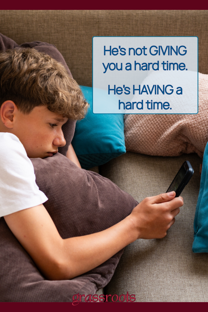 Pin image of teen boy alone on couch staring into his iPhone; text overlay that reads: He's not giving you a hard time; He's having a hard time. Concept of creating emotional safety in relationships with teens